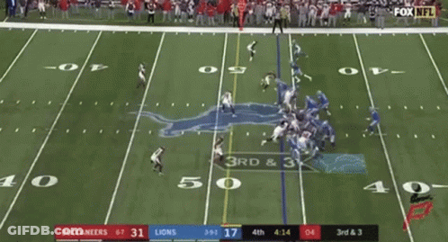 A Football Game Is Being Played On A Field With A Crowd Watching . GIF