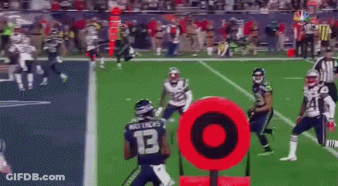 A Football Game Is Being Played On A Field With A Red Target In The Foreground GIF