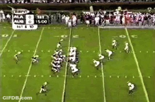 A Football Game Is Being Played On A Field With A Scoreboard In The Background . GIF