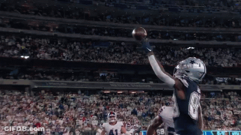 A Football Player Catches A Ball In A Stadium That Has The Word Cowboys On It GIF