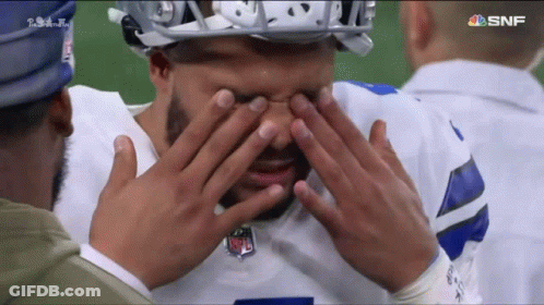 A Football Player Covering His Eyes With His Hands While Another Man Looks On GIF