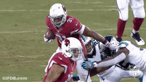 A Football Player For The Cardinals Is Being Tackled By Another Player GIF