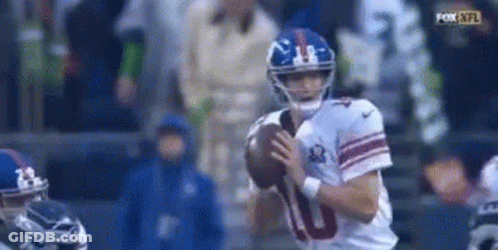 A Football Player For The New York Giants Is Holding A Football In His Hands . GIF