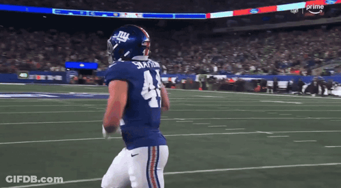 A Football Player For The New York Giants Is Walking On The Field GIF