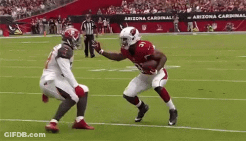 A Football Player From The Arizona Cardinals Is Running With The Ball While Another Player Tries To Stop Him . GIF