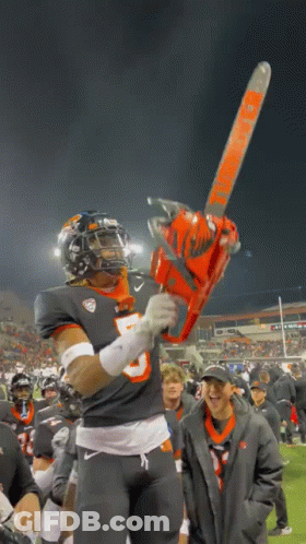 A Football Player Holding A Chainsaw That Says Timberwolf On It GIF