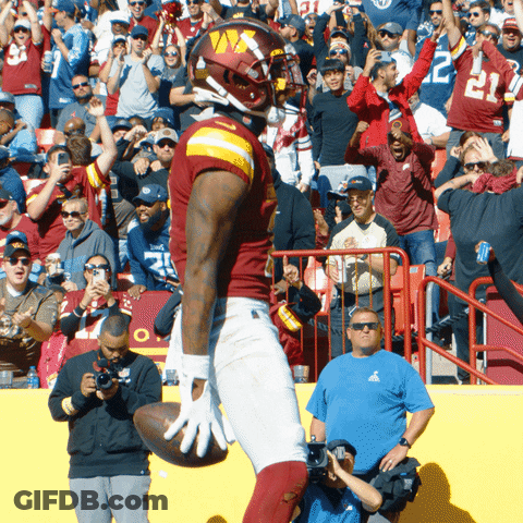 A Football Player Holds A Ball In Front Of A Crowd With The Number 22 On His Shirt GIF