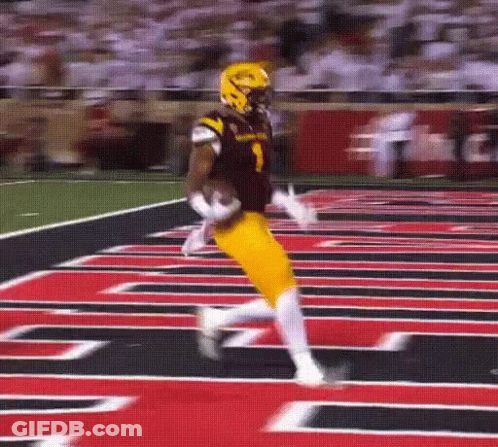A Football Player In A Black And Yellow Uniform Is Running On The Field GIF