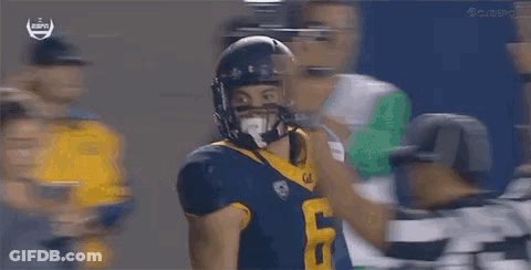 A Football Player In A Helmet Is Being Tackled By Another Player . GIF