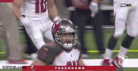 A Football Player In A Helmet Is Kneeling On The Field . GIF