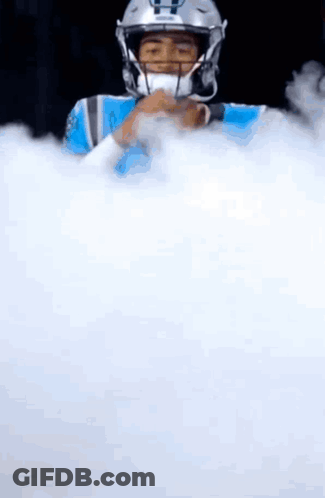 A Football Player In A Helmet Is Surrounded By White Smoke . GIF