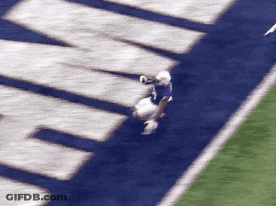 A Football Player In A Purple Jersey Is Being Tackled GIF