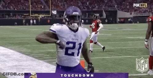 A Football Player In A Purple Jersey Is Running Down The Field . GIF