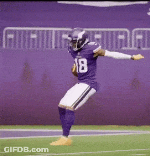 A Football Player In A Purple Uniform Is Jumping In The Air On The Field . GIF
