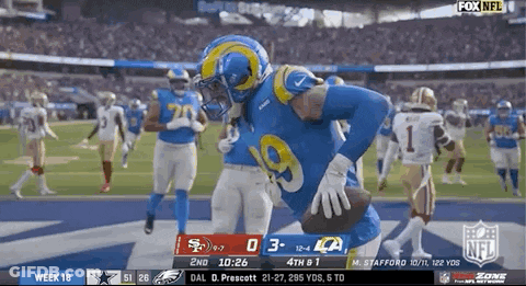 A Football Player In A Rams Uniform Is Running With The Ball During A Game . GIF