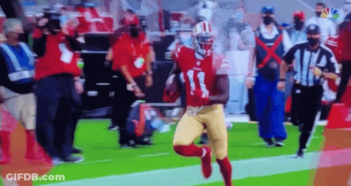 A Football Player In A Red And Gold Uniform Is Running With The Ball On A Field . GIF
