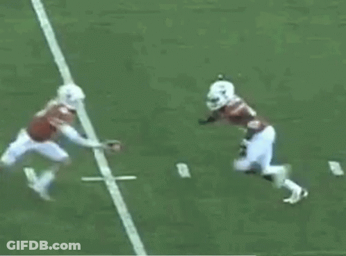 A Football Player In A Red Jersey Is Being Tackled By Another Player In A White Jersey GIF
