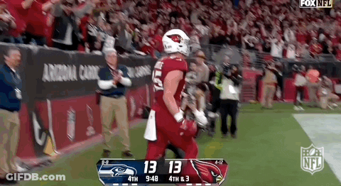 A Football Player In A Red Uniform Is Running On The Field During A Game Against The Seahawks . GIF