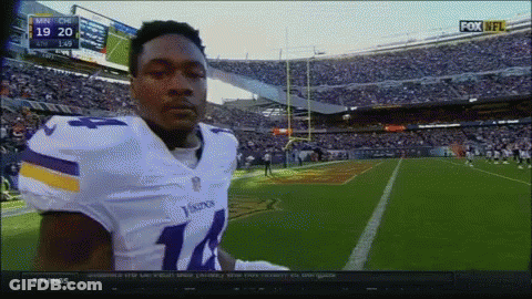 A Football Player In A Vikings Uniform Stands In Front Of A Crowd GIF