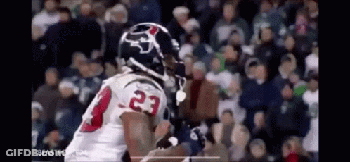 A Football Player In A White Jersey With The Number 23 On It Is Running With The Ball In Front Of A Crowd . GIF