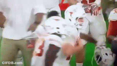 A Football Player Is Being Helped Off The Field By A Group Of People . GIF