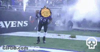 A Football Player Is Dancing On The Field While A Fireworks Display Is Going On In The Background . GIF