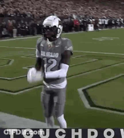 A Football Player Is Dancing On The Field With The Word Touchdown In The Corner . GIF