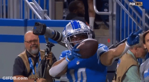 A Football Player Is Holding A Football In His Hands While A Cameraman Takes A Picture Of Him GIF