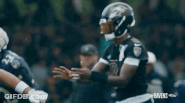 A Football Player Is Holding A Football In His Hands While Standing On A Field . GIF