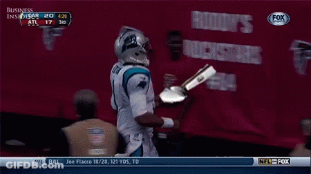 A Football Player Is Holding A Trophy In Front Of A Banner That Says Business GIF