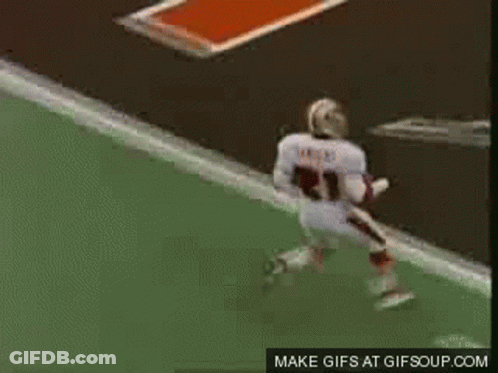 A Football Player Is Jumping In The Air While A Referee Watches . GIF