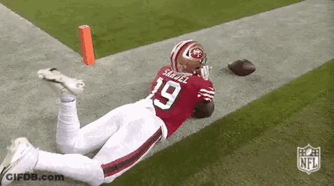 A Football Player Is Laying On His Stomach On The Field While Holding A Football . GIF