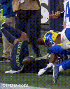 A Football Player Is Laying On The Field With His Knee Up GIF