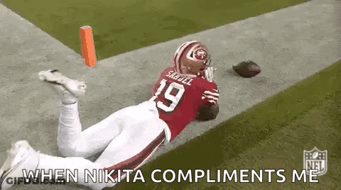 A Football Player Is Laying On The Ground On A Field With A Football . GIF