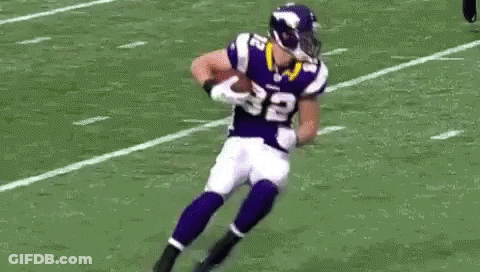 A Football Player Is Laying On The Ground While Another Player Tries To Tackle Him . GIF