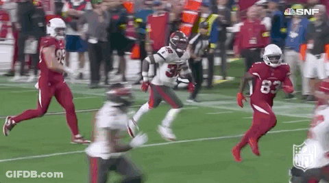 A Football Player Is Running On A Field During A Game . GIF