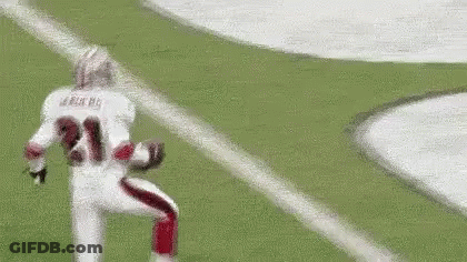 A Football Player Is Running On A Field With A Ball In His Hand . GIF
