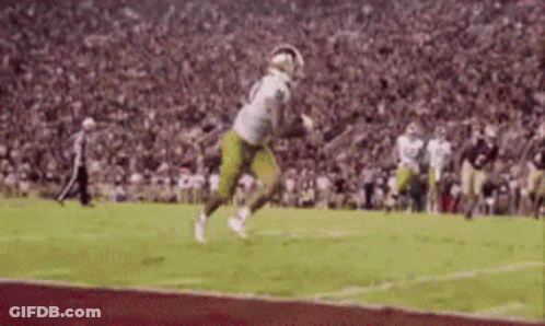 A Football Player Is Running On A Field With A Ball In His Hand . GIF