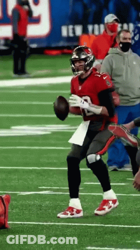 A Football Player Is Running On A Field With A Ball In His Hand . GIF