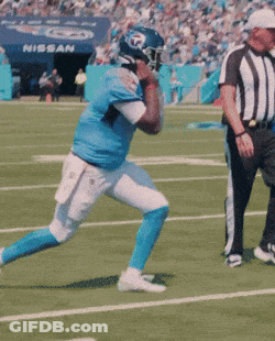 A Football Player Is Running On A Field With A Referee And A Nissan Sign In The Background GIF