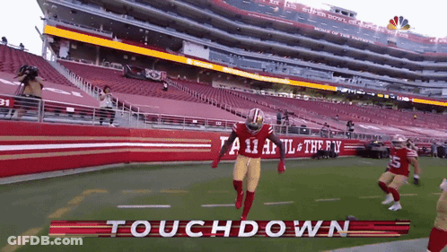 A Football Player Is Running On A Field With The Words Touchdown Written On It GIF
