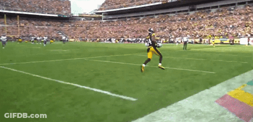 A Football Player Is Running On The Field During A Game . GIF