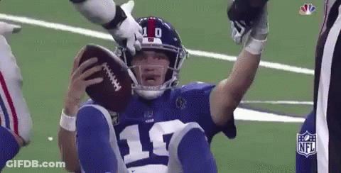 A Football Player Is Sitting On The Ground Holding A Football In His Hand . GIF