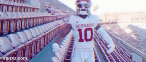 A Football Player Is Standing In A Stadium With Empty Seats . GIF