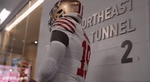 A Football Player Is Standing In Front Of A Northeast Tunnel Sign . GIF