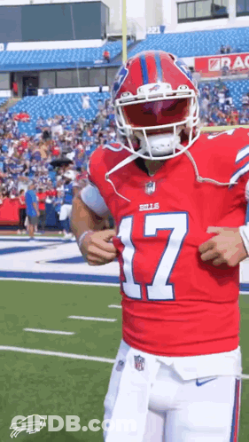A Football Player Is Standing On A Field Wearing A Red Jersey And A Helmet . GIF