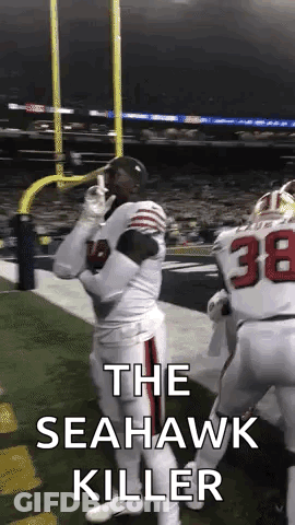 A Football Player Is Standing On The Field With The Words `` The Seahawk Killer '' Written On The Bottom . GIF