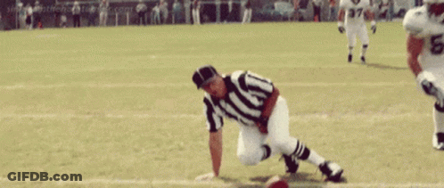 A Football Player Is Throwing A Ball In Front Of A Crowd Of People . GIF
