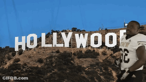 A Football Player Stands In Front Of A Hollywood Sign GIF