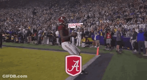 A Football Player Stands In Front Of A Touchdown Banner GIF